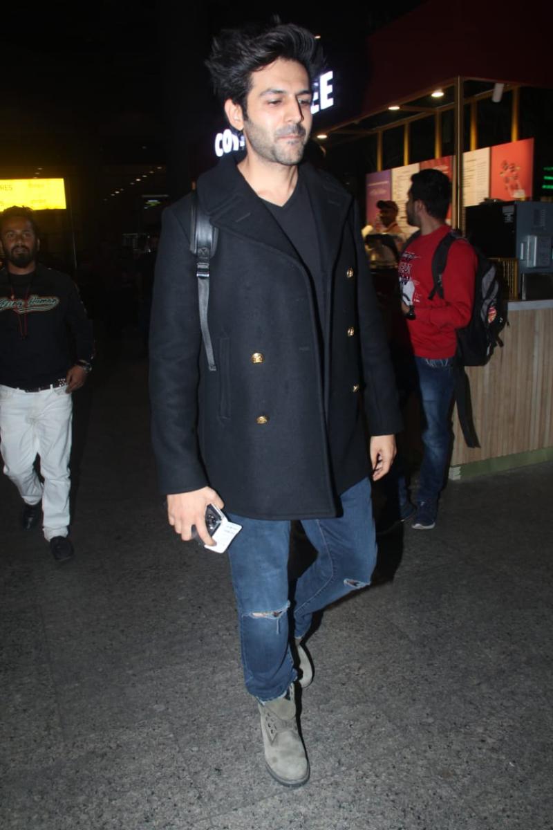 Keep calm and stay warm: The 'Freddy' star, Kartik Aaryan beats the cold in style as he arrives wearing a chic black overcoat with knee-slit jeans. 